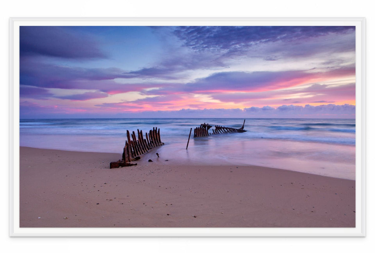 Wall art print of a wreck on a beach with a colorful sunset sky