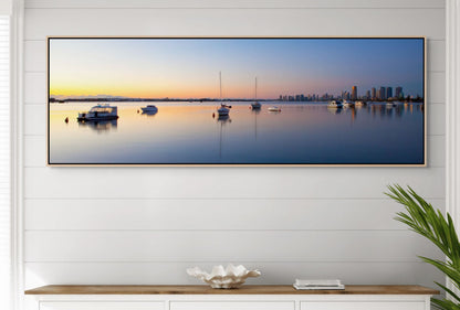 Panoramic wall art of a coastal sunset over gold coast skyline with boats on water, displayed in a modern interior setting. 