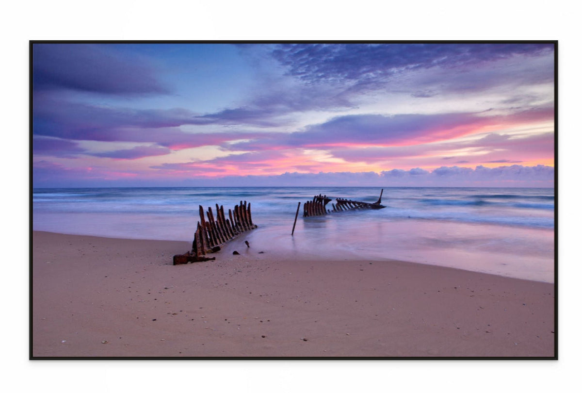 Canvas print dicky Beach scene with a shipwreck at sunset, featuring a colorful sky.