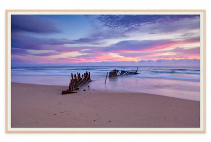 Beach scene with shipwreck and colorful sunset sky wall art print