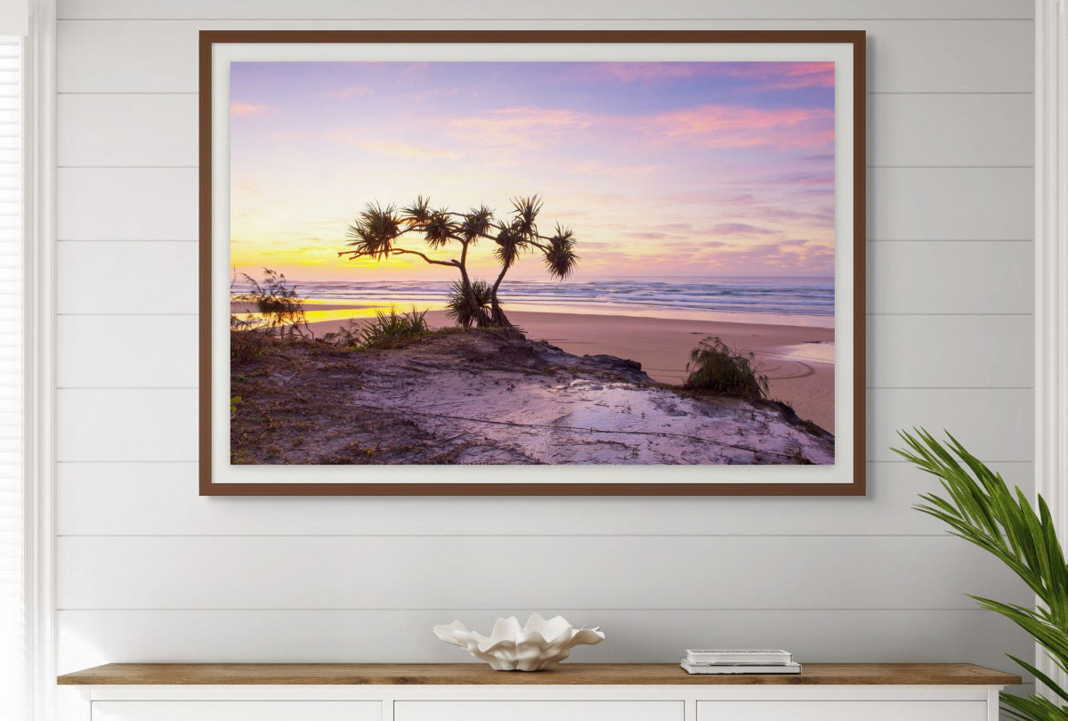 Framed beach sunset print on a wall above a console table.
