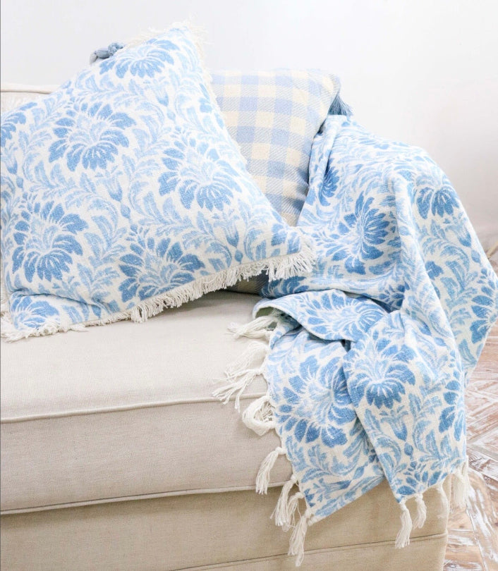 Blue floral-patterned blanket draped over a light-colored sofa.