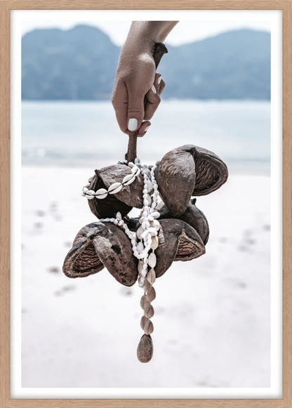 Wall art print of Hand holding a decorative shell and bead ornament with a blurred natural background.