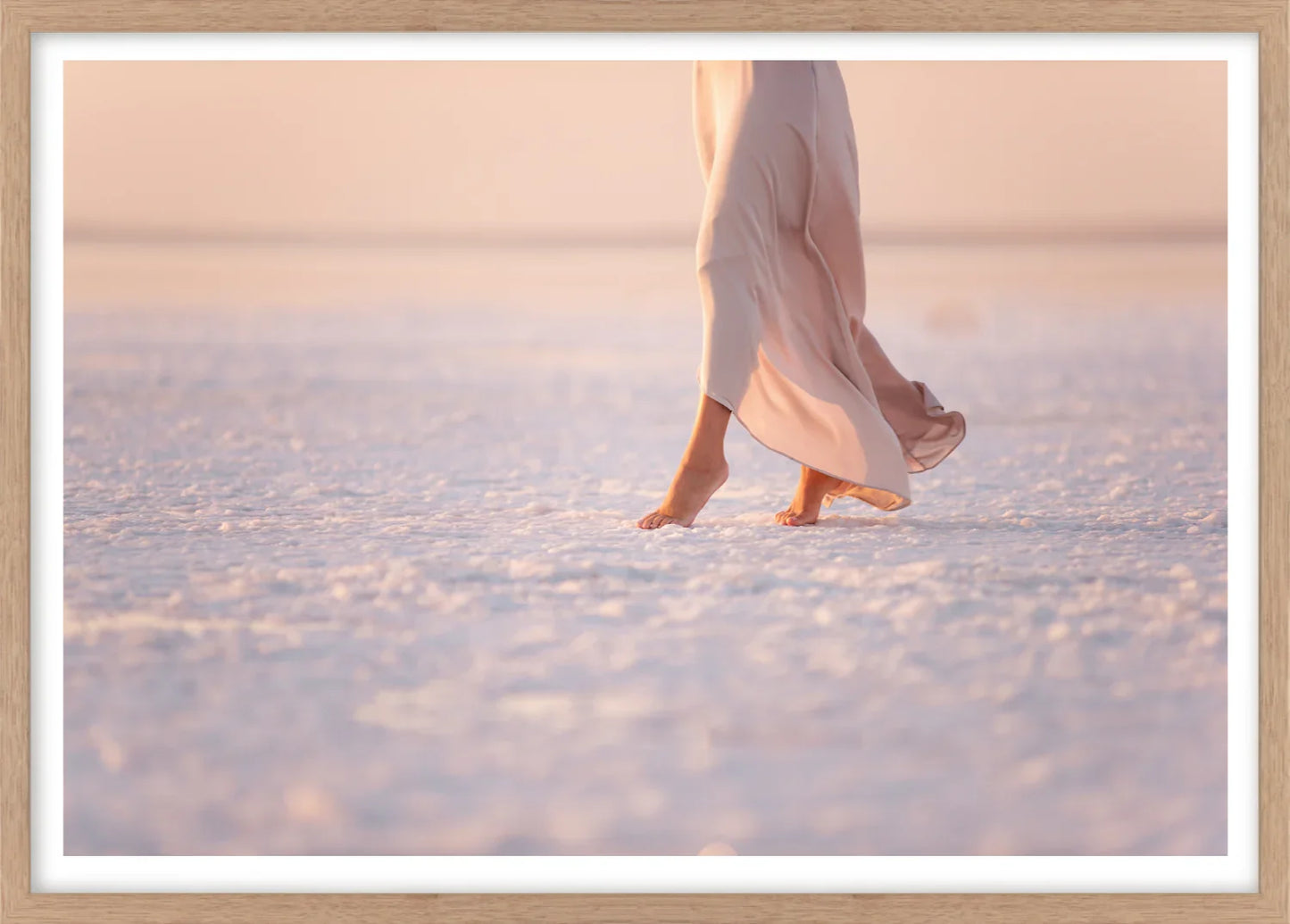 Framed wall art of lady in pink dress walking on a salt flat at sunset.