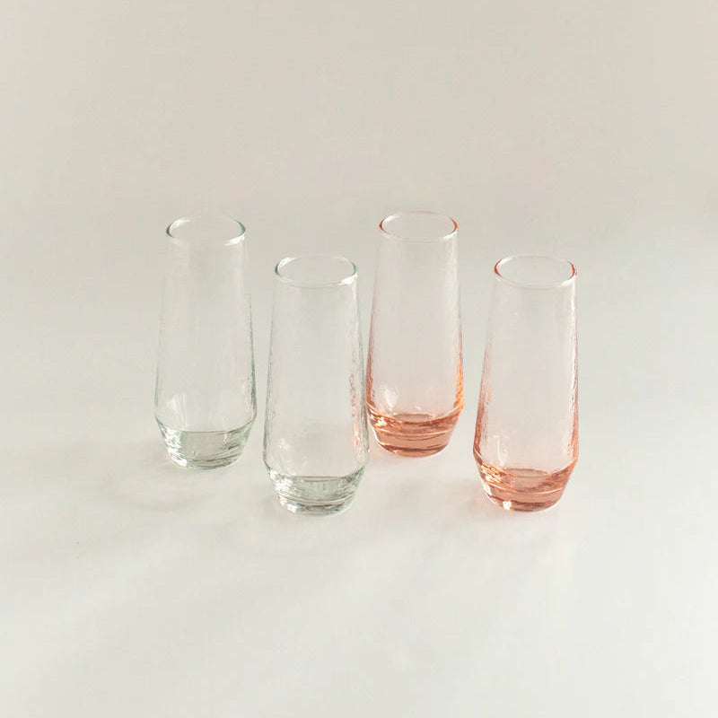 Set of four glass tumblers with pink and clear designs on a light background