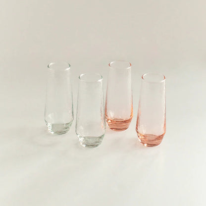 Set of four glass tumblers with pink and clear designs on a light background