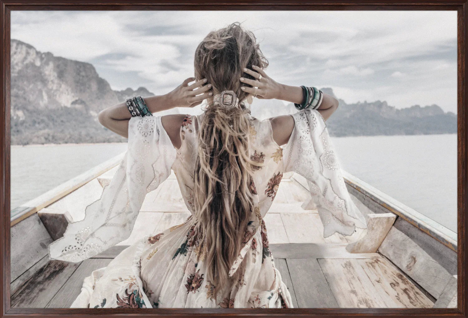 Wall art print of boho lady with long hair sitting on a boat with mountains in the background